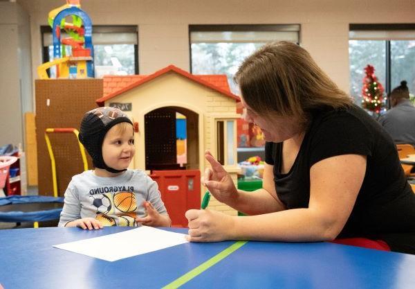 Teacher showing young boy sign language